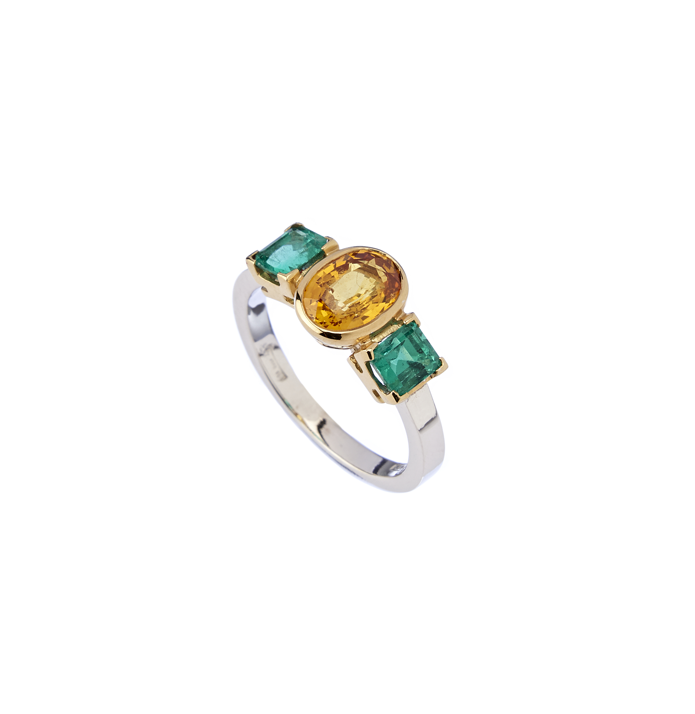 anello con zaffiro giallo e smeraldi su sfondo bianco
