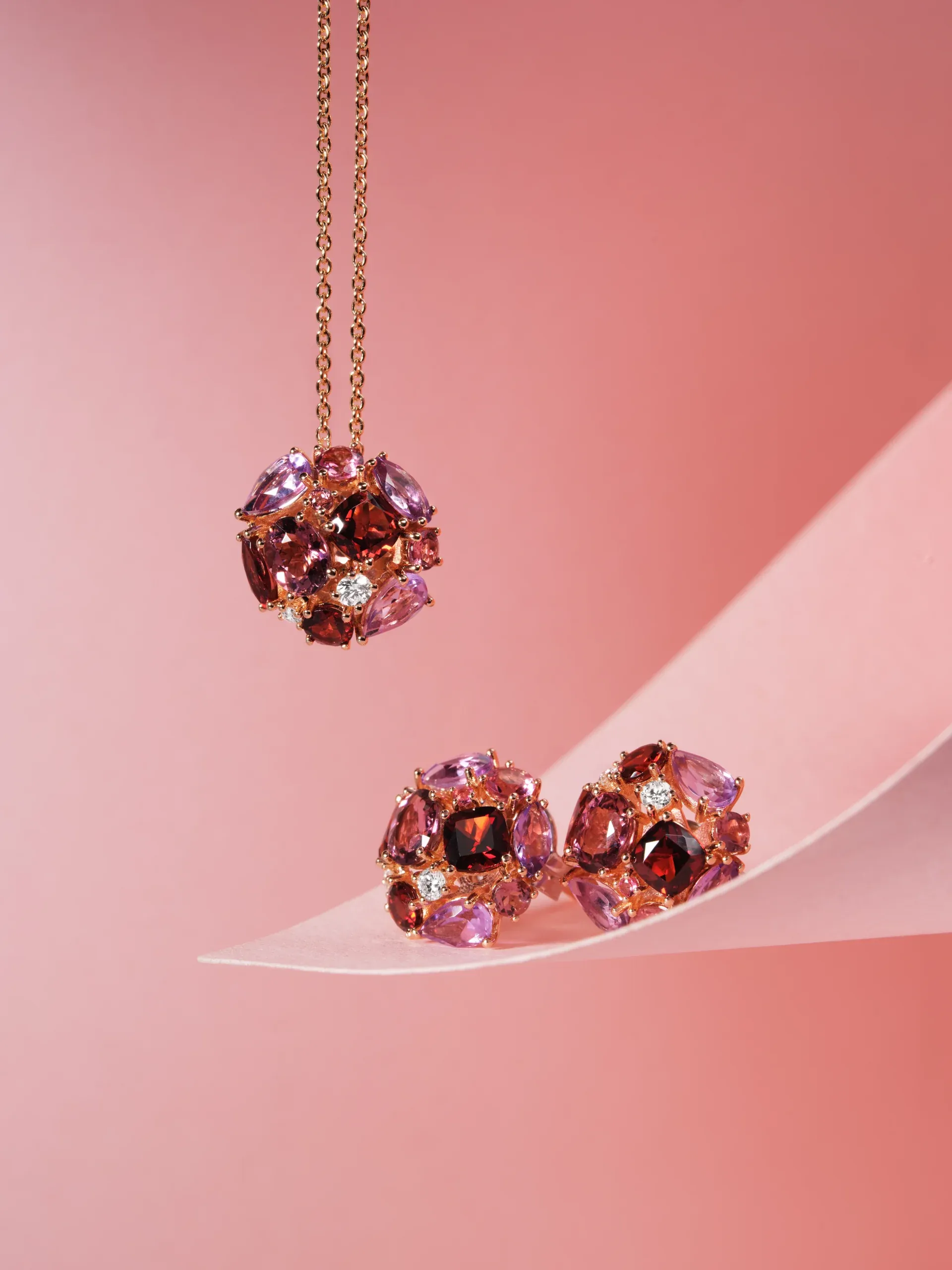 Iris pendant and earrings with red stones on a pink background – Ponte Vecchio Gioielli