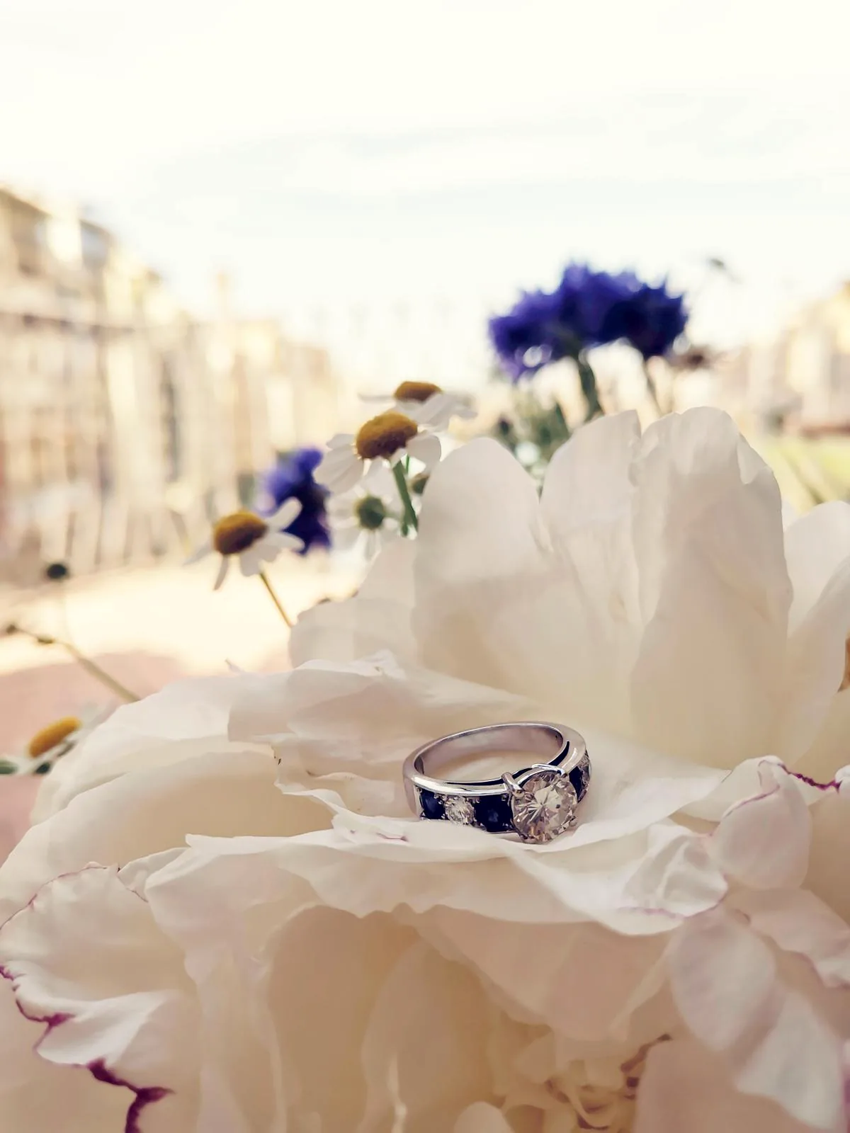 A solitaire ring resting on a white peony, on the shop terrace